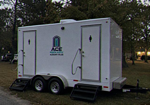 Restroom trailer rental parked on grass at an evening event
