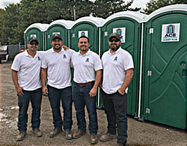Delivery and service crew standing in front of the porta potty rental fleet