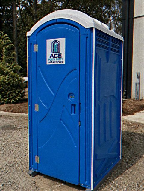 Standard porta potty rental unit set up outside a commercial building